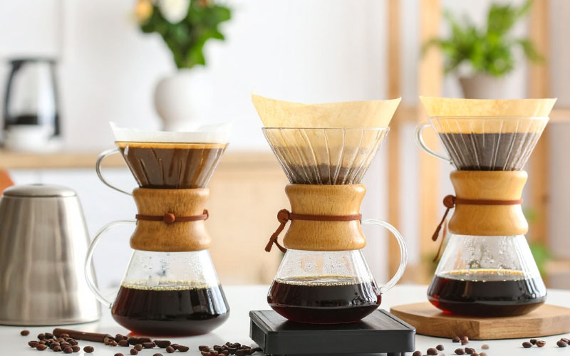 A gooseneck kettle pouring hot water in a circular motion over a pour-over dripper.