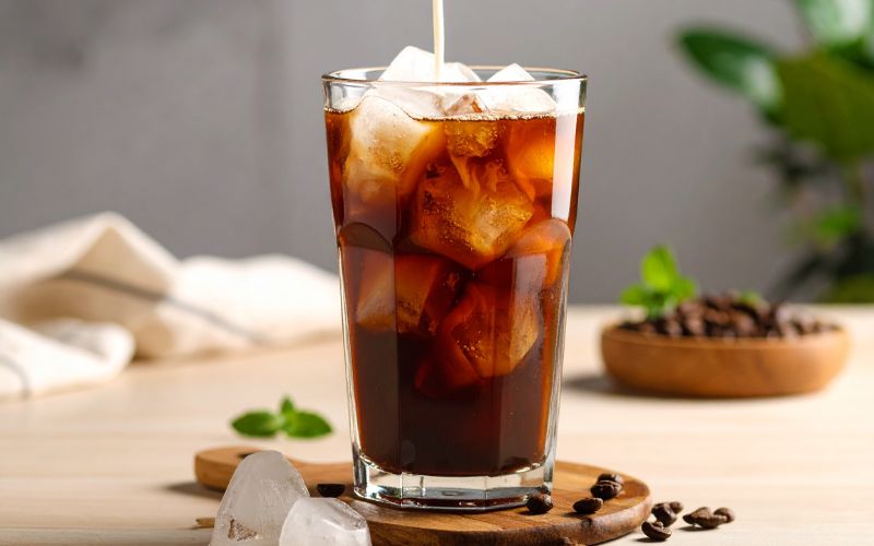 A large glass jar filled with coffee grounds and water, steeping to become cold brew concentrate.