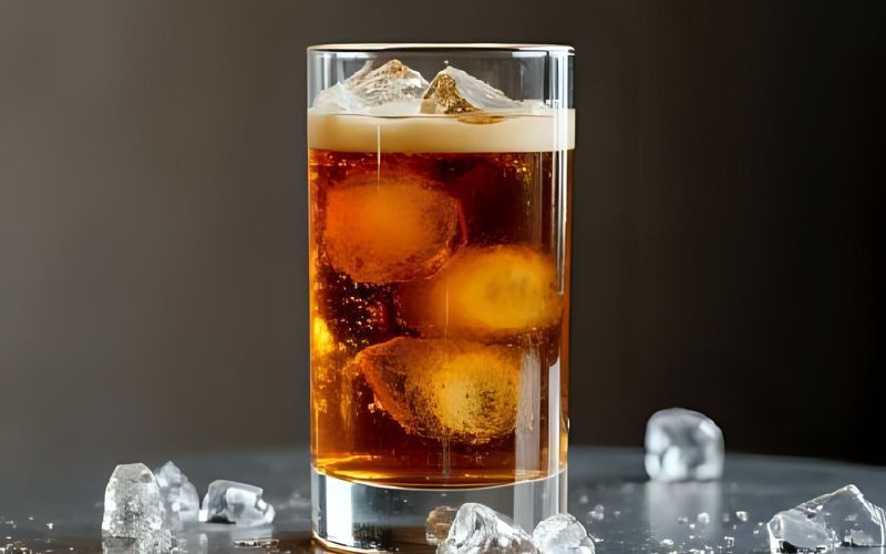 A tall glass filled with ice and tonic water, with a shot of espresso being poured over the top, creating a beautiful layered effect.