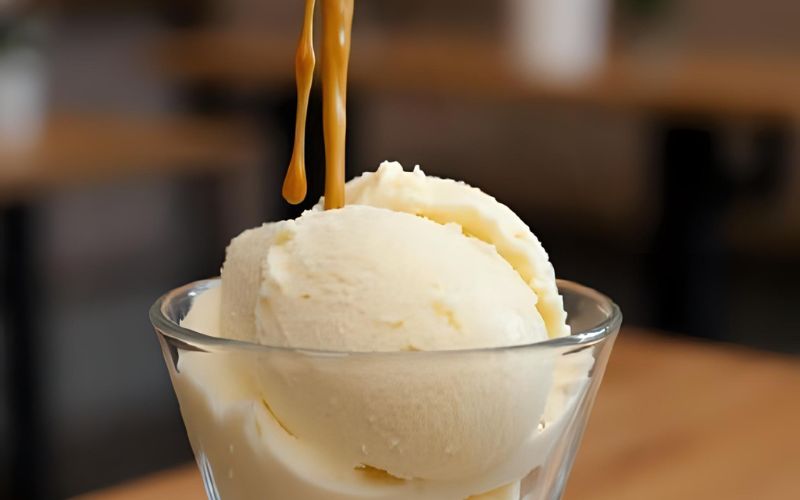 A scoop of vanilla ice cream in a glass, with a shot of dark espresso being poured over it.