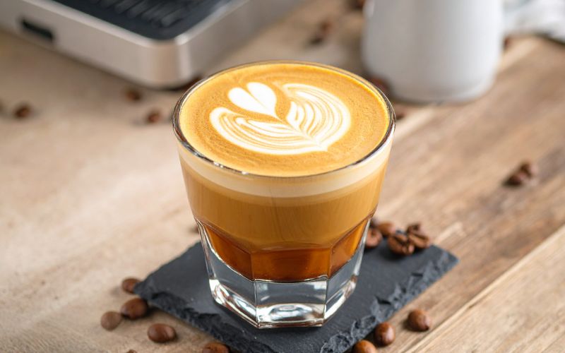 A small glass (like a Gibraltar glass) filled with a Cortado, showing a perfect mix of espresso and microfoam.