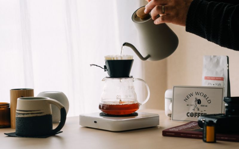 A pour-over dripper brewing hot coffee directly into a glass server filled with ice cubes, showcasing the Japanese iced coffee method.