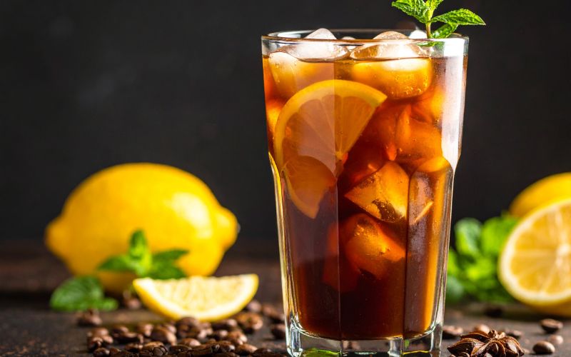 A tall glass filled with ice and lemonade, with a shot of coffee being poured in, creating a layered effect.